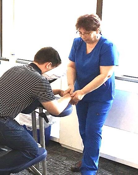 Dianne performing seated chair massage on a client at a workplace event